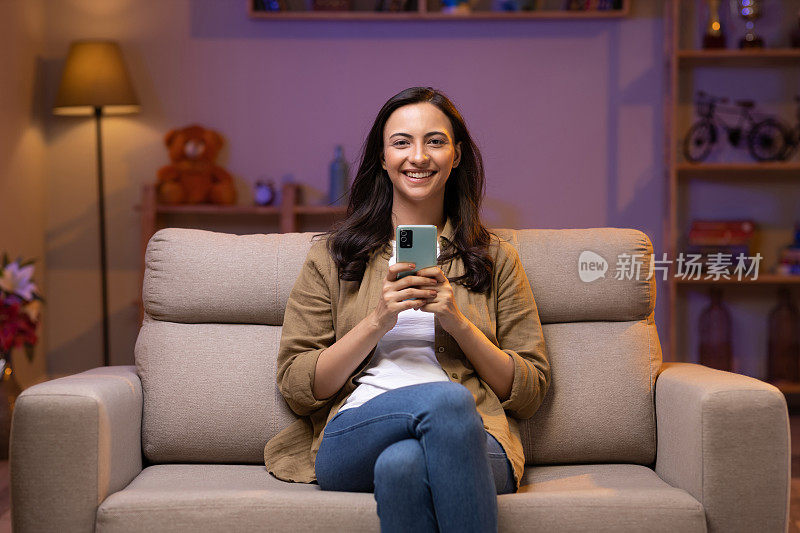 Young woman using photo sitting on sofa at home stock photo